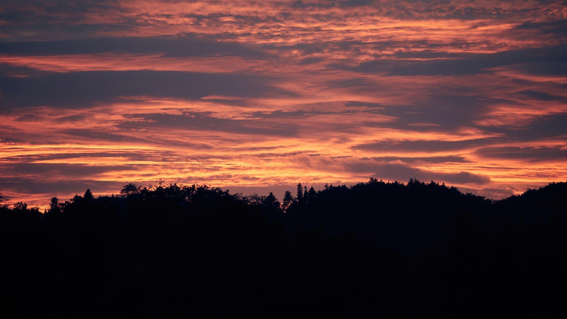 Sonnenuntergang hinter bewaldetem Bergland